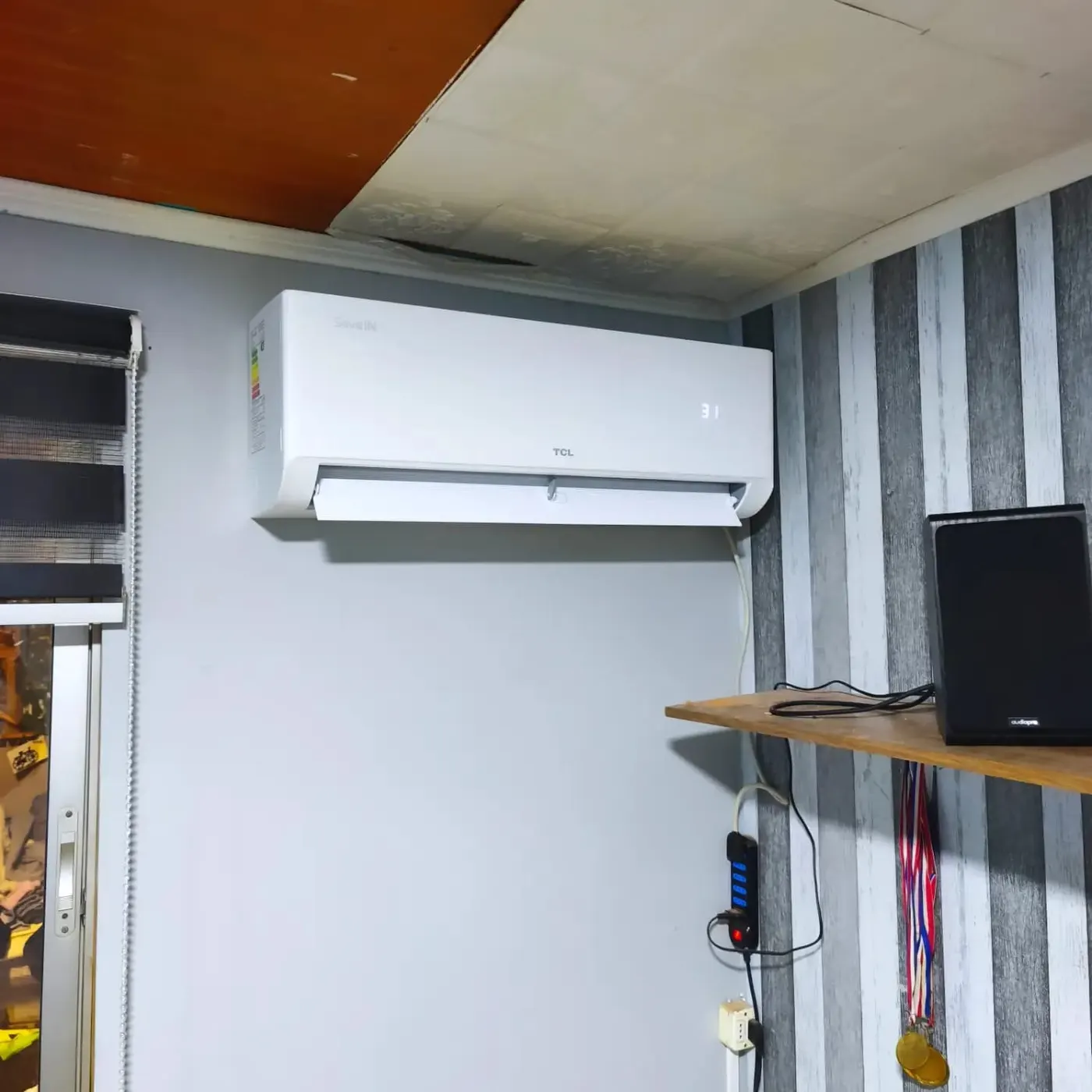 Equipo TCL encendido marcando 31 grados en el living de una casa.