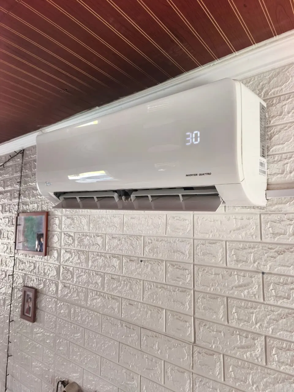 Equipo inverter encendido marcando 30 grados, instalado bajo el cielo de madera de una terraza.